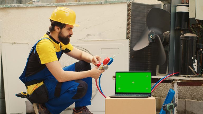 Certified technician hired by home owner to detect cause of damage to air conditioner, checking freon level values measured by professional manifold meters, displayed on chroma key laptop