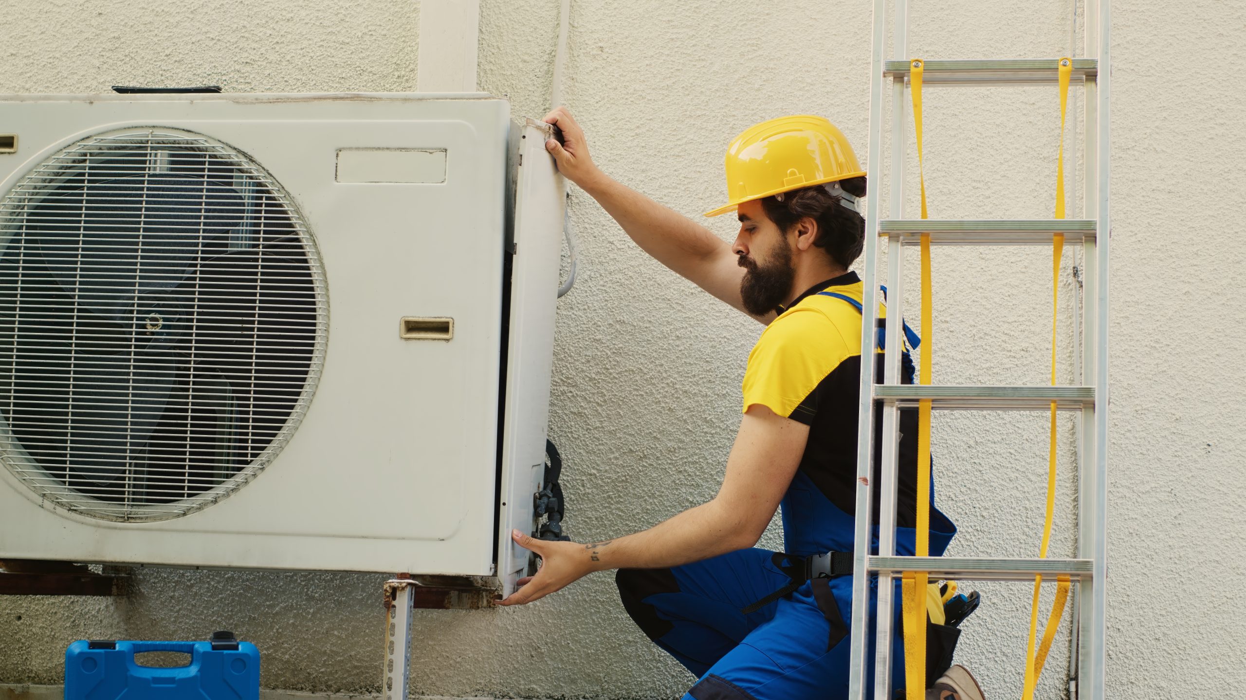 Experienced wireman dissasembling external air conditioner metal side coil panel to check for bad wiring. Meticulous electrician doing repairing on malfunctioning hvac system